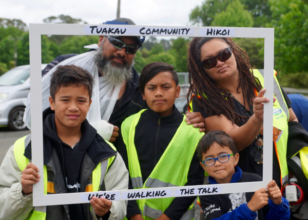 A family of five pose within an image frame reading Tuakau community hīkoi. We're walking the talk