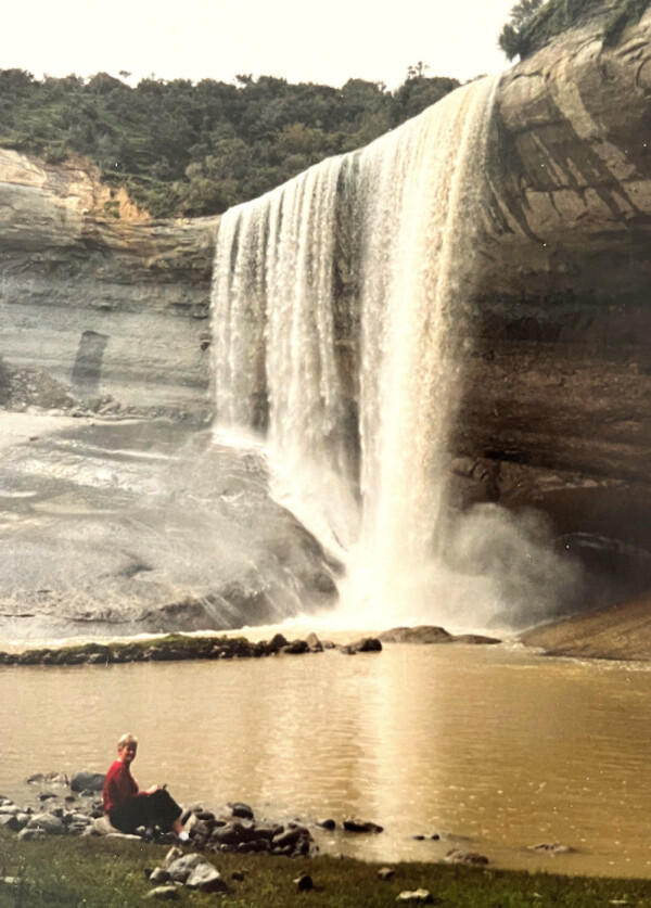 A visitor sitting on a rock beside the pool at the base of Mangatiti Falls.